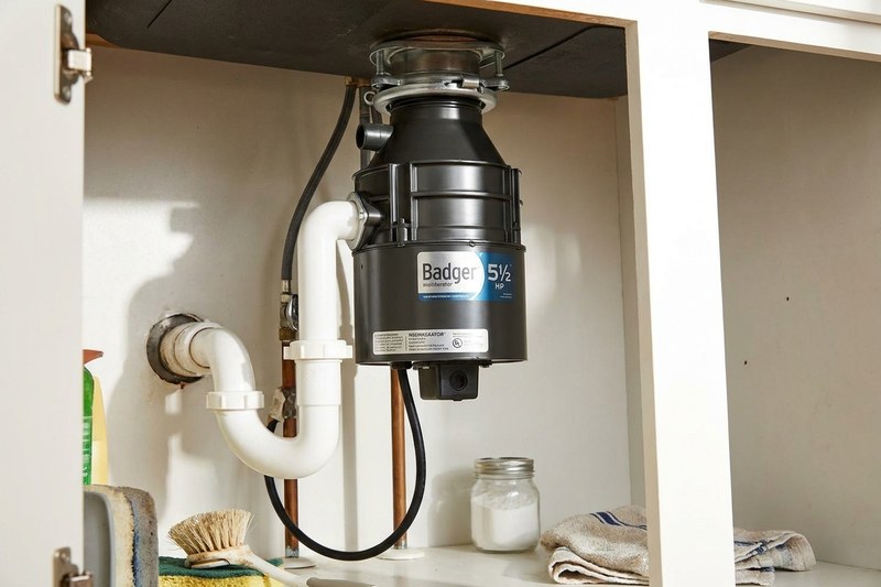 Garbage disposal mounted under a kitchen sink with drain plumbing